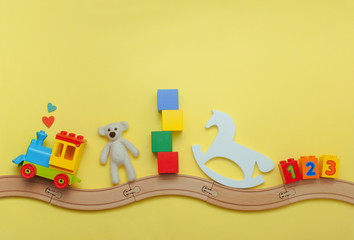 Kids toys on toy wooden railway on yellow background