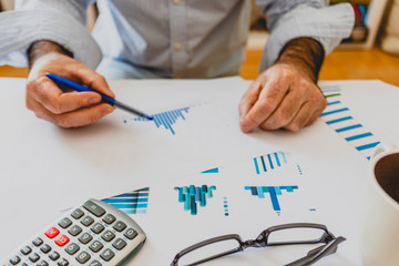 Calculator, pen and glasses with financial graphs.