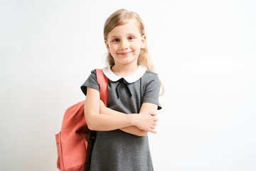Little girl photographed against white background wearing school uniform dress isolated holding a...