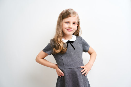 Little girl photographed against white background wearing school uniform dress isolated