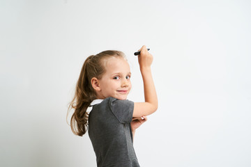 Little girl photographed against white background wearing school uniform dress isolated is mocking...