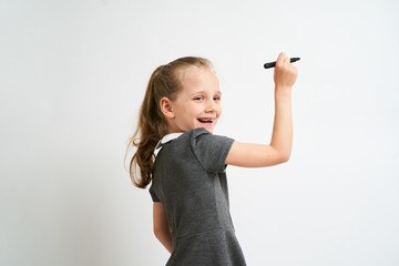 Little girl photographed against white background wearing school uniform dress isolated is mocking...