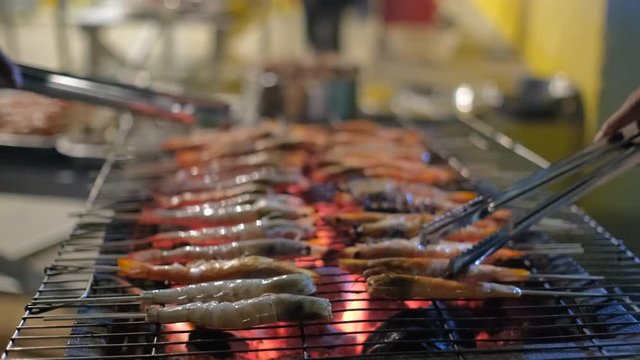 Fresh shrimp or prawn grilled bbq seafood on charcoal stove for night party. Royalty high-quality free stock video footage of grilling fresh prawns or shrimps on the flaming barbecue grill
