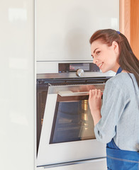 Beautiful woman in the kitchen, waiting with the front of the oven