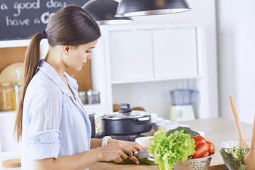 A young woman prepares food in the kitchen. Healthy food - vege