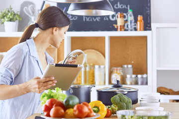 Image of a young pretty girl standing in the kitchen and is coo