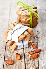 Fresh Italian cookies cantuccini stackes and almond nuts on ructic wooden table background.
