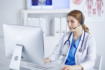 Portrait of a happy smiling young doctor in headset in office