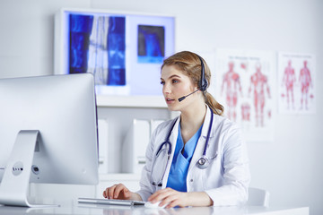 Portrait of a happy smiling young doctor in headset in office