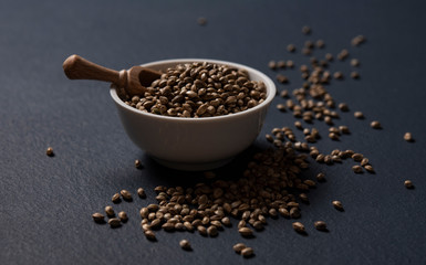 hemp seeds scattered dark blackground close up