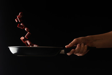 Chef is cooking pepperoni sausages, on a black background, a recipe book, German sausages, beer snacks