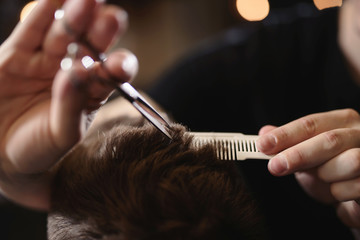 Close up barber's hands cuts hair with scissors and beard of men in the barbershop, hairdresser...