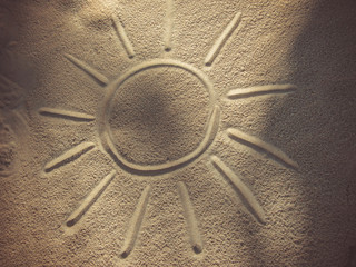 Drawing of the sun on the sand of the beach
