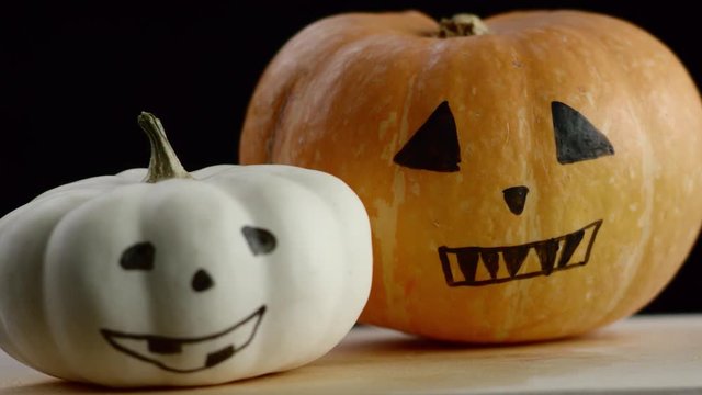 video shows two painted pumpkins, black background, the focus is on white pumpkin
