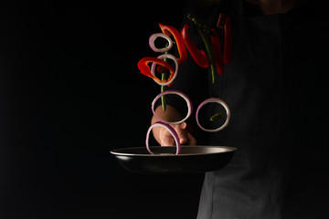 Chef preparing pepperoni sausages with green beans, sweet bell peppers and red onion rings, on a...