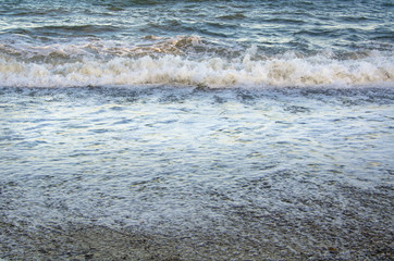 Colorful seascape, white foam of wave on beach close up
