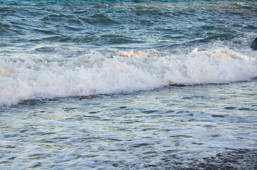 Colorful seascape, white foam of wave on beach close up
