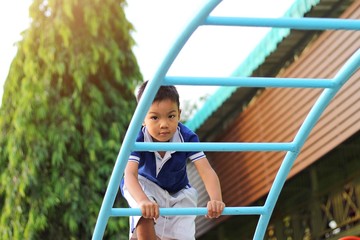 Obraz premium Happy asian child boy playing and climbing a steel bar toy at the playground. Kid and sport concept.