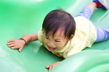 Asian baby child girl crying and sad because she falling from a slider bar toy at the playground.