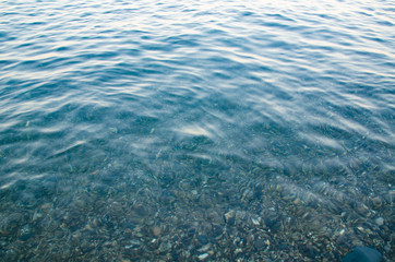 Abstract sea background, view on ripple surface of water, stone bottom underwater