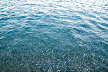 Abstract sea background, view on ripple surface of water, stone bottom underwater