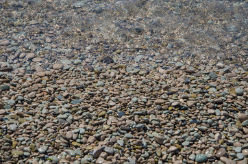 Background of seashore, pebble beach and transparent sea top view