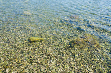 Abstract sea background, view on ripple surface of water, stone bottom underwater