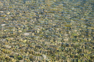 Abstract sea background, view on ripple surface of water, stone bottom underwater