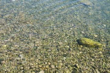 Abstract sea background, view on ripple surface of water, stone bottom underwater