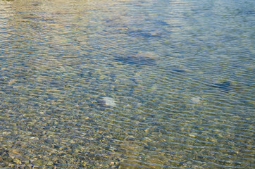 Abstract sea background, view on ripple surface of water, stone bottom underwater