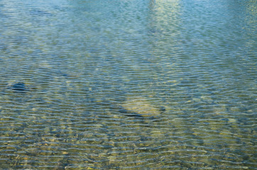 Abstract sea background, view on ripple surface of water, stone bottom underwater