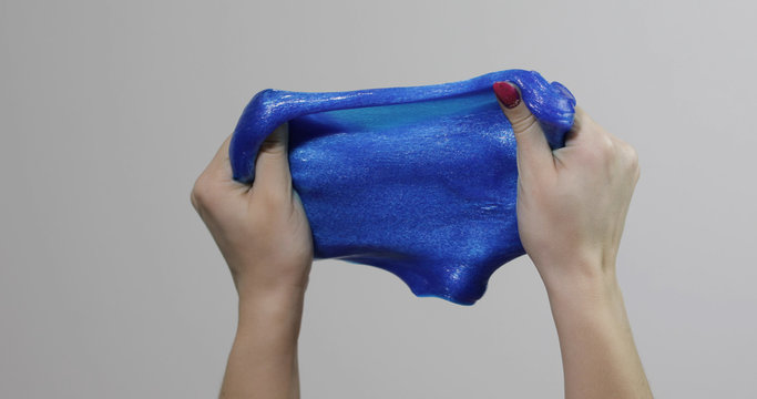 Woman hands playing with oddly satisfying blue slime gooey substance. Antistress