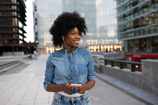 attractive dark skinned girl is listening to music chatting with friends smiling booking tickets online banking
