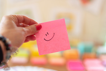 Closeup of pink sticky note with smiley face