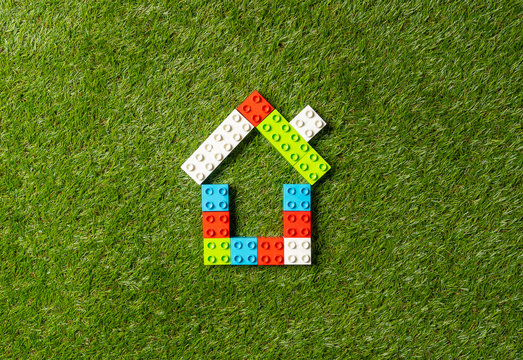 Colorful toy blocks house on grass in conceptual image of Investment business and Property industry