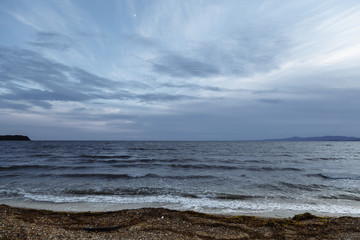 A coast of a cold grey sea. on the shore of the cold gray sea. Dirty, polluted shore. Seashore with a lot of waste