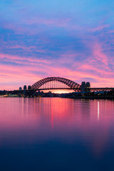 Silhouet van Sydney Harbour Bridge bij dageraad met blauwe en paarse lucht.