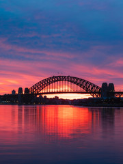 Silhouette of Sydney Harbour Bridge with colorful sky at dawn.