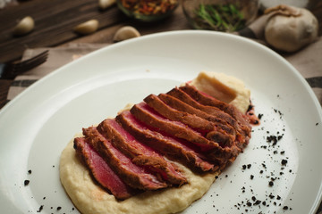 Beef with garlic and mashed potatoes. Cafe menu on a wooden background in warm colors with copy space.