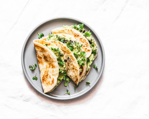 Avocado eggs greens salad paratha flatbread quesadilla on a light background, top view