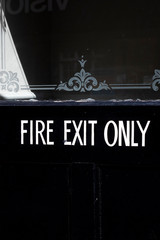 emergency fire exit only sign on black painted timber door to retail premises