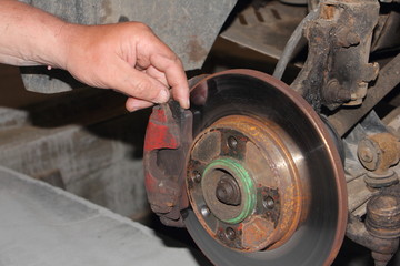 Checking the thickness of the brake pads, car service - hand points your finger at the brake caliper