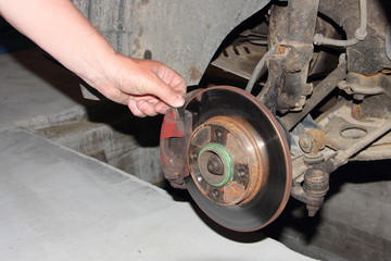 Checking of the brake disc, and brake pads, car brakes inspection - hand points your fingers at the brake caliper