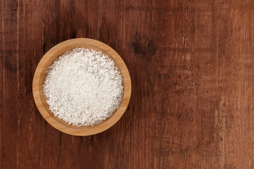 Fototapeta na wymiar A bowl of coarse sea salt, shot from above on a dark rustic wooden background with a place for text
