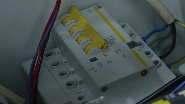 Hands of electrician with screwdriver tighten up switching electric actuator equipment in fuse box.  Electrical terminal box. man checking the electric control box. overload relay. 