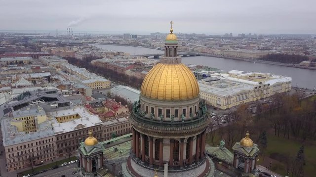 Aerial view; drone flight near the gilded dome of St. Isaac's Cathedral, Exterior Isaakievskiy Sobor, Saint Petersburg, Russia; typical cloudy gray weather near Baltic sea
