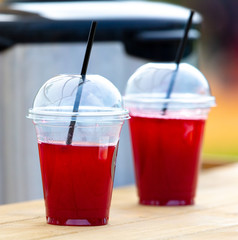 A plastic glass with a red drink is on the table