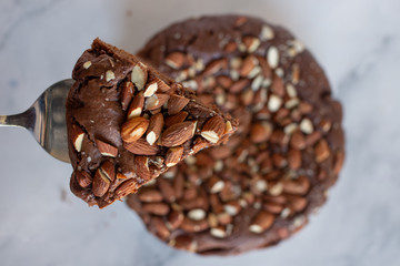 Piece of stack homemade dark chocolate brownies with salted almonds on a table