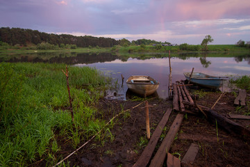 Picture of a row boat on Russian river Nerl on sunset. Blue sky and amazing clouds