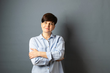 Portrait of a young woman with a short haircut on gray blank background. Human emotions facial expression happiness joy.